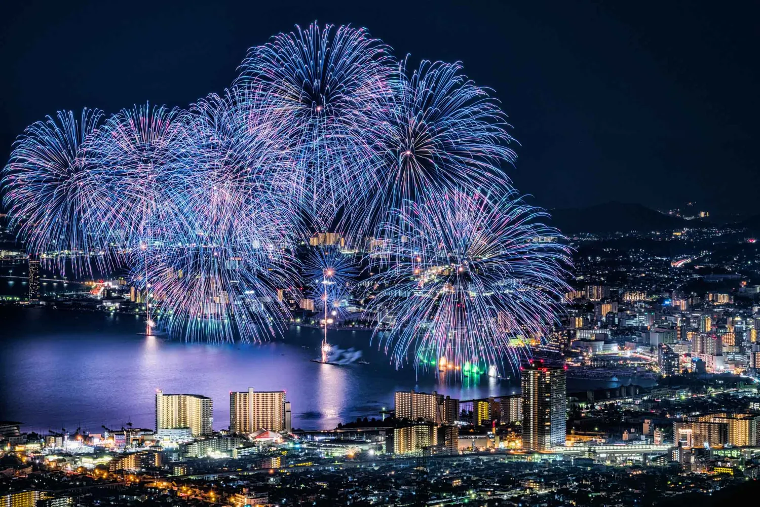 Fireworks over a lakeside city at night